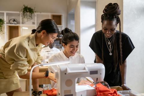Fashion designers consulting over sewing machine